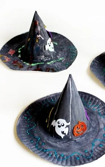 Child making a paper plate witch hat for Halloween craft activity