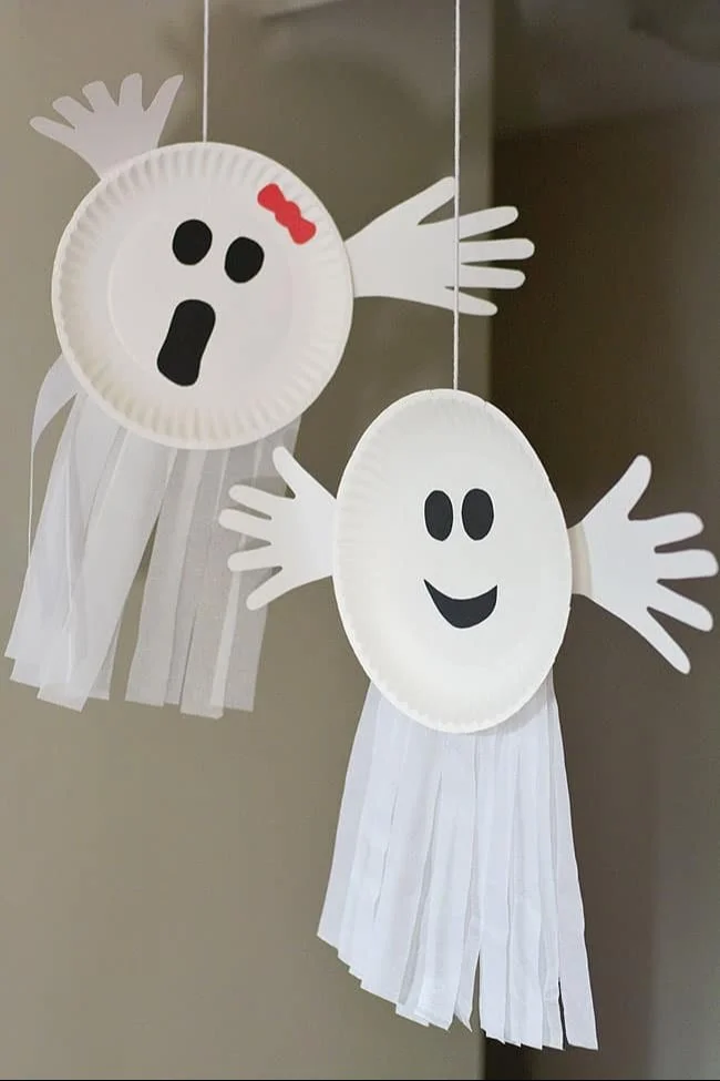 Child making a paper plate ghost craft for Halloween