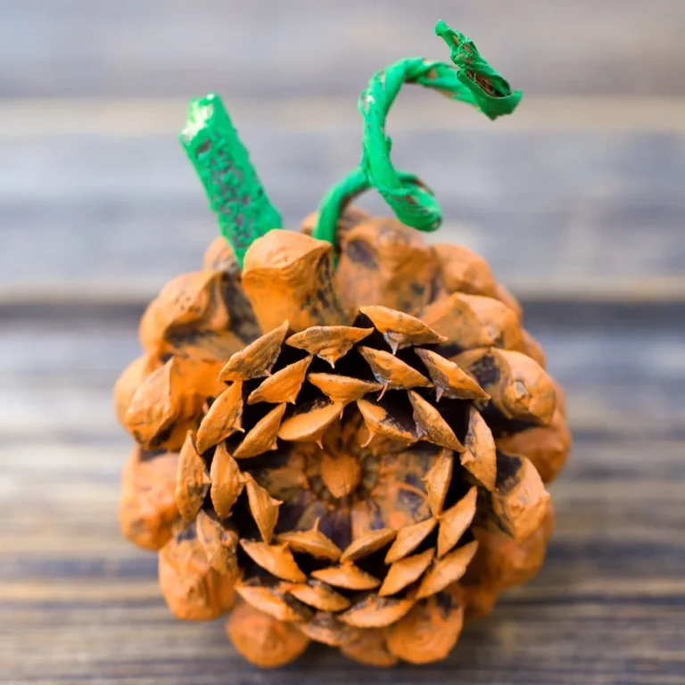 A crafted pine cone pumpkin surrounded by autumn decorations